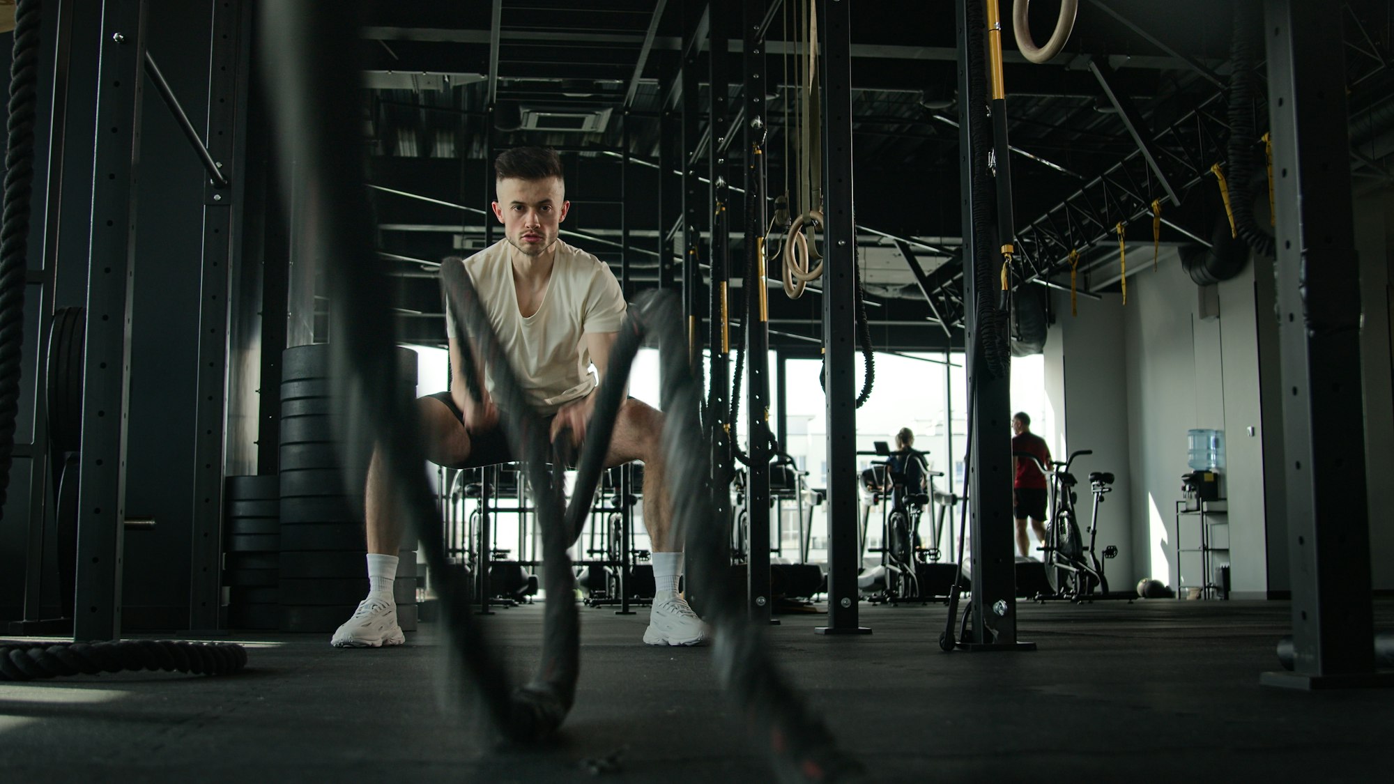 Caucasian fitness man exercising with battle rope cross training in gym strong muscular sportsman