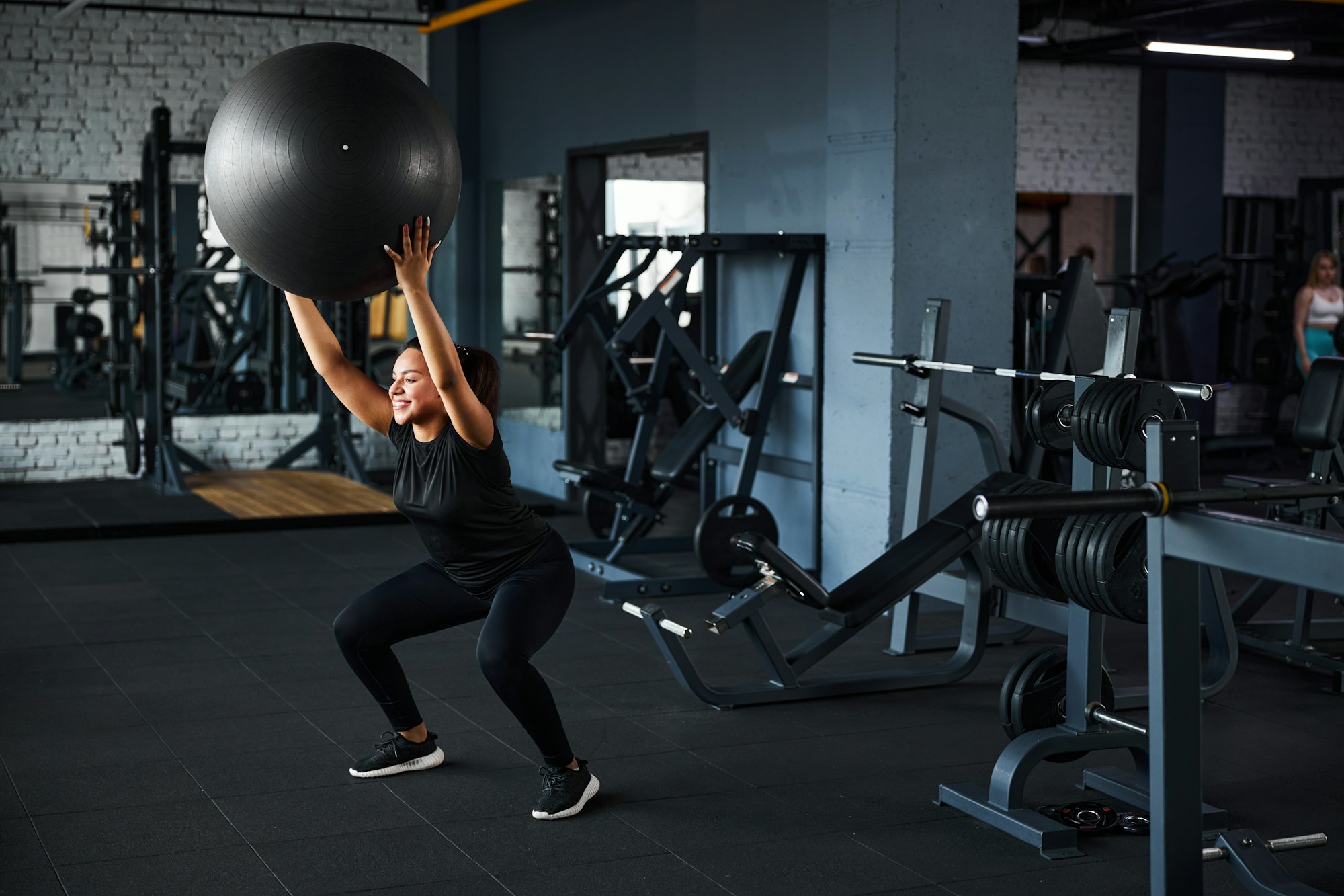 Cheerful female doing full body workout in gym